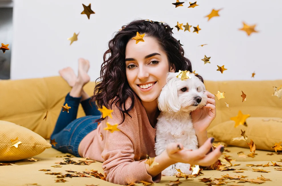 Woman laying on sofa holding a puppy dog