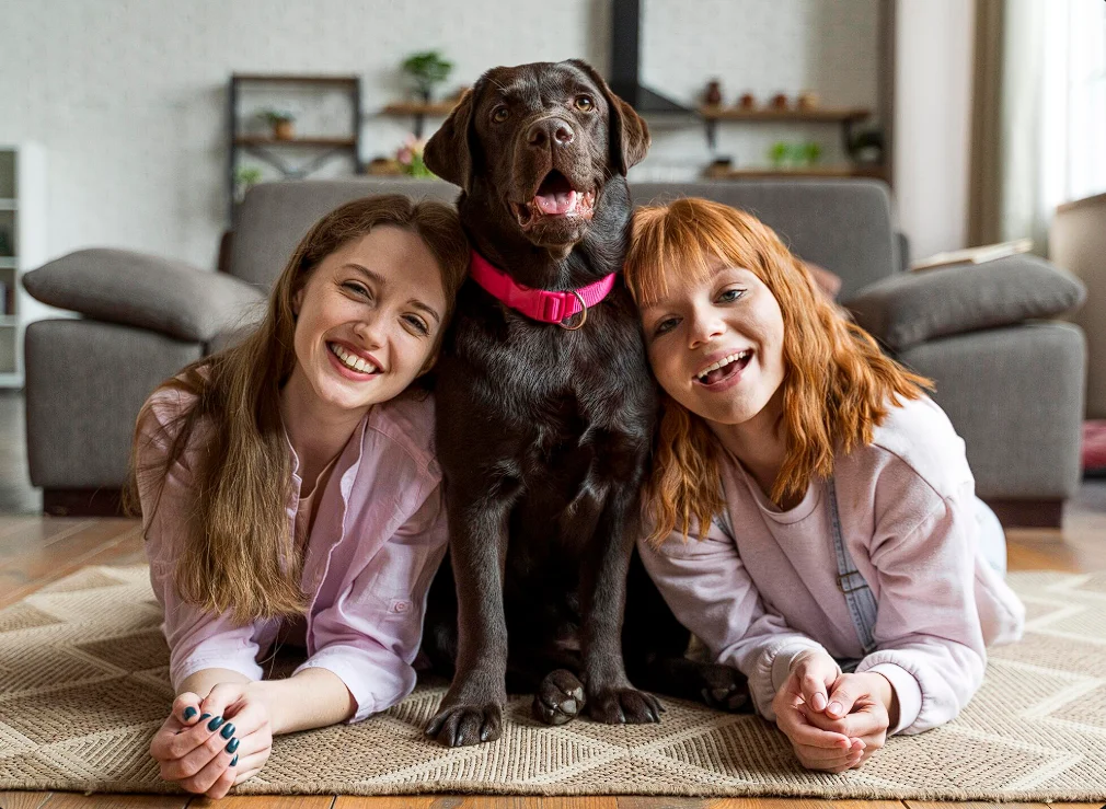 2 girls laying down with a pet dog
